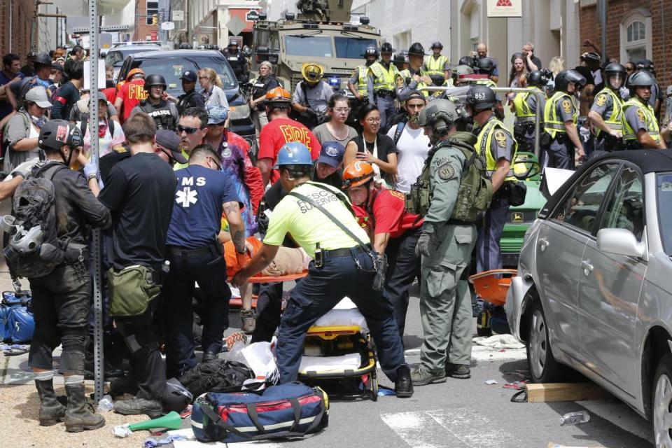 Violence: Rescue personnel help injured people after a car ran into a large group of protesters (AP)