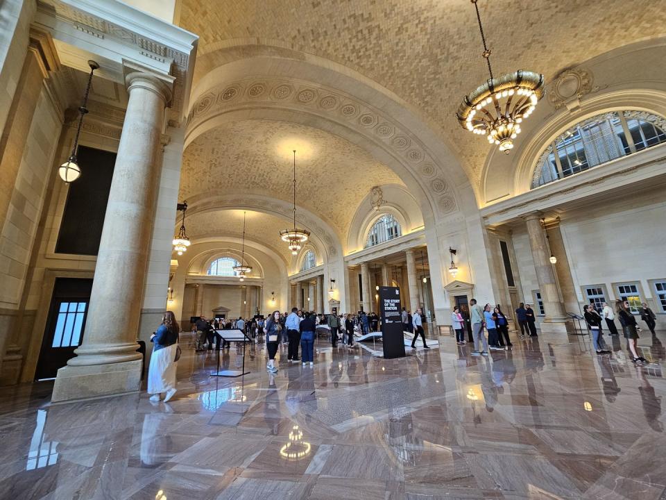 a large room with people and chandeliers