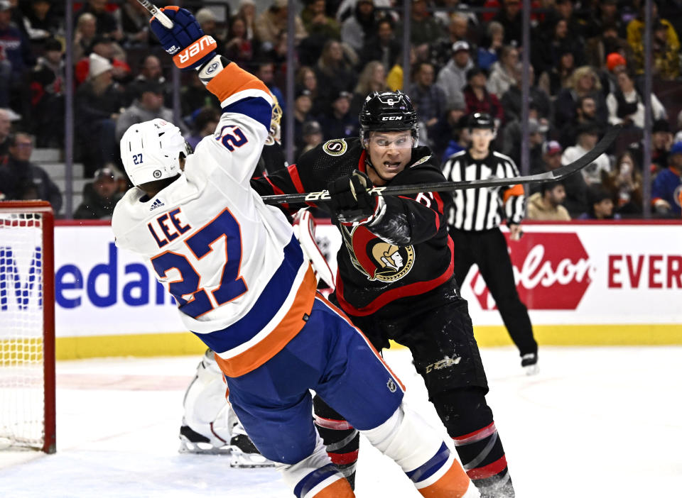 Ottawa Senators defenseman Jakob Chychrun, right, checks New York Islanders left wing Anders Lee (27) during first-period NHL hockey game action in Ottawa, Ontario, Friday, Nov. 24, 2023. (Justin Tang/The Canadian Press via AP)