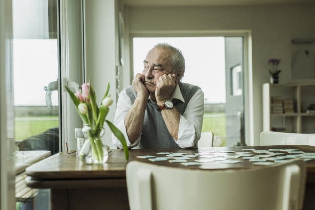 Portrait of sad senior man looking through window