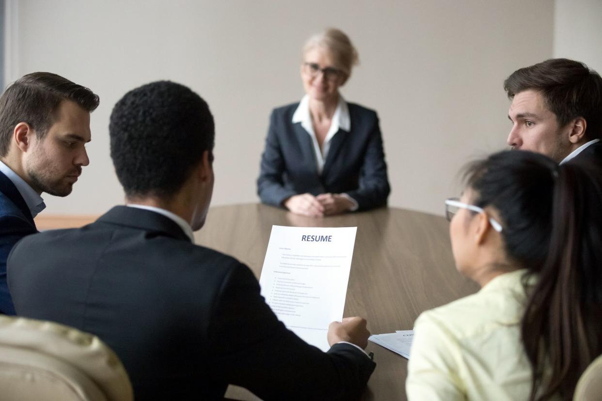 senior woman in interview, millennials looking at resume in foreground