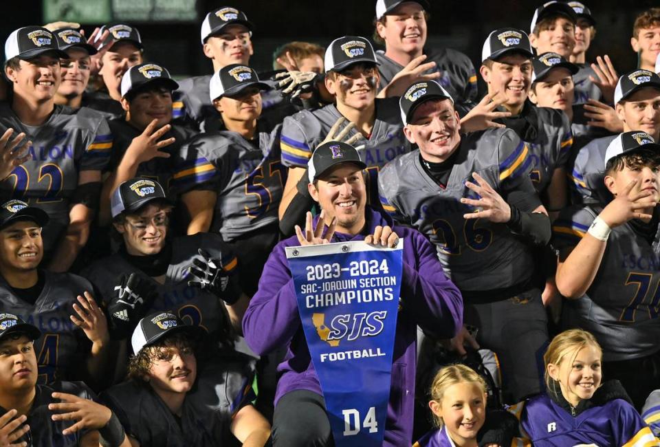 Head Coach Andrew Beam and his players pose for pictures with the Section banner at St. Mary’s High School in Stockton, Calif., Friday, Nov. 24, 2023.