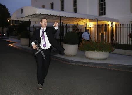 A U.S. Secret Service agent with an automatic rifle hurries people to evacuate the White House complex over a security alert moments after President Barack Obama and his family left for the presidential retreat, Camp David, in Maryland, September 19, 2014. REUTERS/Larry Downing