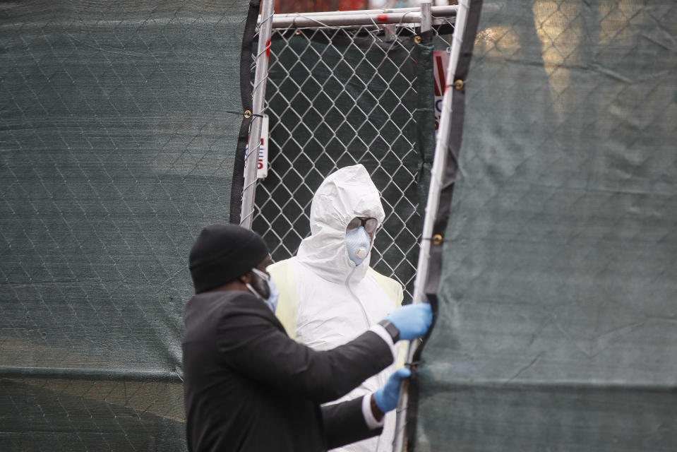 Medical workers wearing personal protective equipment due to COVID-19 concerns as an attendant pulls a fence closed to conceal operations at The Brooklyn Hospital Center, Thursday, April 9, 2020, in the Brooklyn borough of New York.New York state posted a record-breaking number of coronavirus deaths for a third consecutive day even as a surge of patients in overwhelmed hospitals slowed, while isolation-weary residents were warned Thursday the crisis was far from over.(AP Photo/John Minchillo)