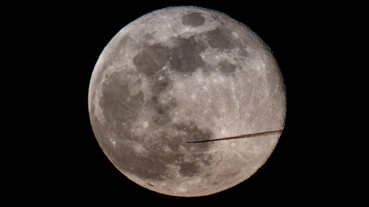 Ein Flugzeug fliegt am Abend am Vollmond vorbei. Foto: Robert Michael