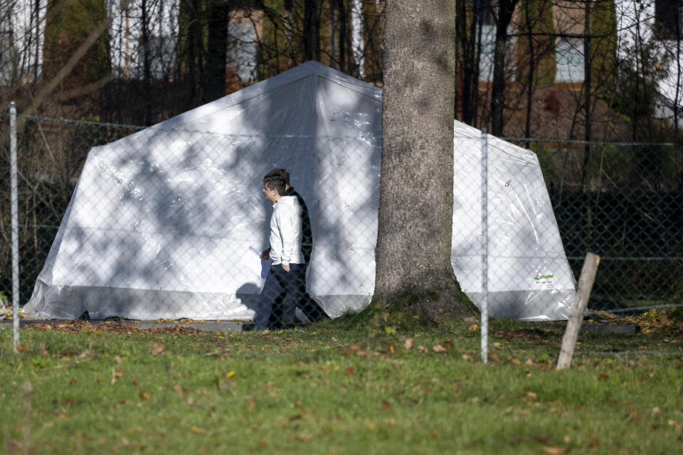 Two men walk in front of a tent that were set up as shelters for refugees in Sankt Georgen im Attergau, Austria, Monday, Nov. 14, 2022. In a weeks-long standoff with the Austrian government over the accommodation of rising numbers of asylum seekers in the alpine country, the mayor of the small village St. Georgen defied national housing measures and ordered the dismantling of more than a dozen tents for some 100 migrants in his community citing security concerns. (AP Photo/Andreas Schaad)