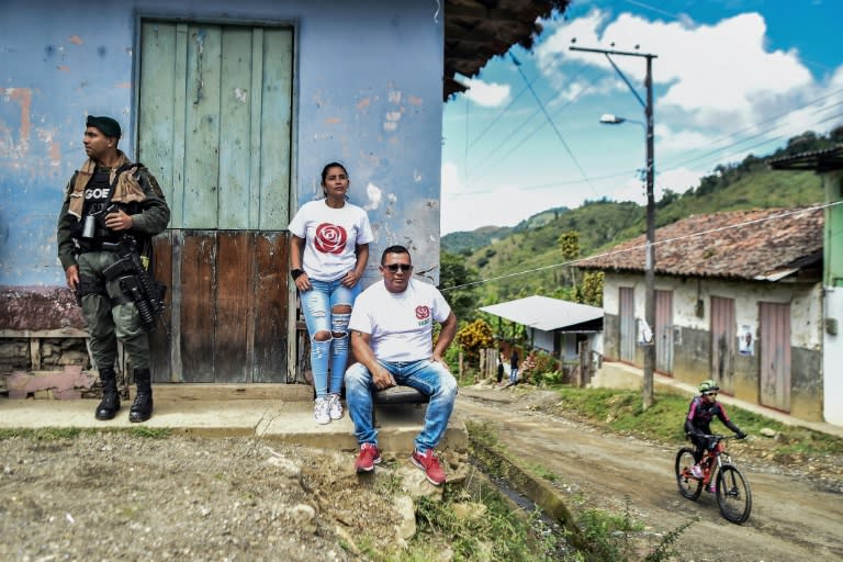 A police officer stands guards next to members of the political party formed by leftist FARC guerrillas under a 2016 peace accord, in Monteloro, Valle del Cauca Department, Colombia