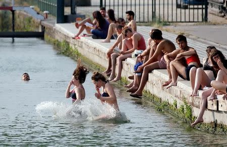 FILE PHOTO - Women dive in the canal at the La Villette park as hot summer temperatures hit Paris, France June 22, 2017. REUTERS/Jean-Paul Pelissier