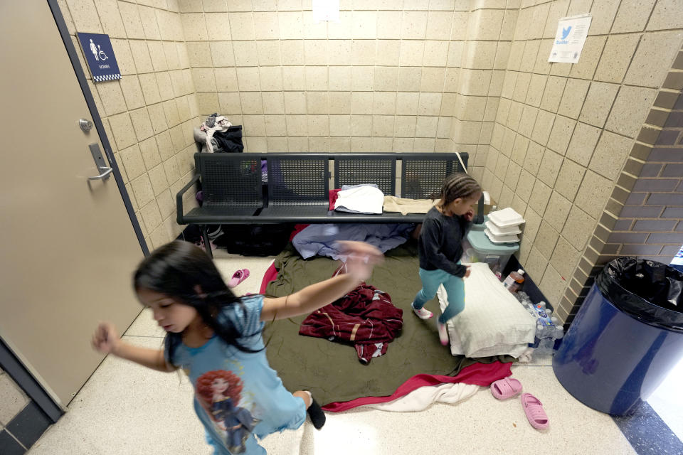 Venezuelan immigrant girls Avril Brandelli, left, and Charlotte, play in an area of the Chicago Police Department's 16th District station where their families have taken shelter on Monday, May 1, 2023. Chicago has seen the number of new arrivals grow tenfold in recent days. Shelter space is scarce and migrants awaiting a bed are sleeping on floors in police stations and airports. (AP Photo/Charles Rex Arbogast)