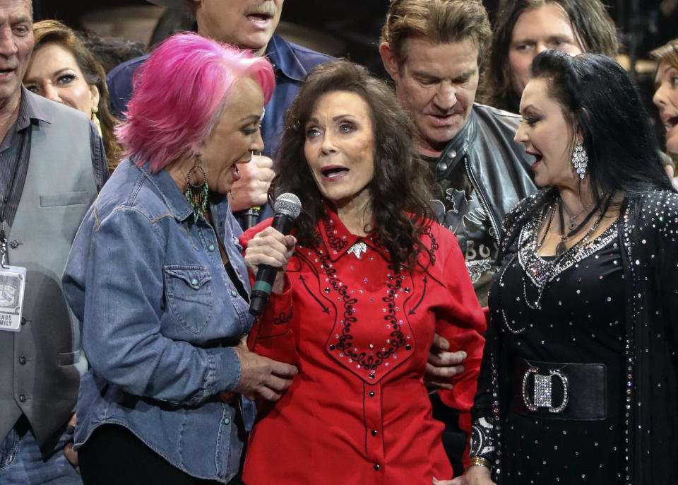 ARCHIVO –Loretta Lynn, centro, Tanya Tucker, izquierda, y Crystal Gayle cantan en el homenaje por el cumpleaños 87 de Lynn en la Arena Bridgestone el 1 de abril de 2019 en Nashville, Tennessee. Lynn, la hija de un minero de carbón en de Kentucky que se convirtió en un pilar de la música country, ha fallecido. La familia de Lynn dijo que murió el 4 de octubre en su casa de Tennessee. Tenía 90 años. (Foto Al Wagner/Invision/AP, archivo)