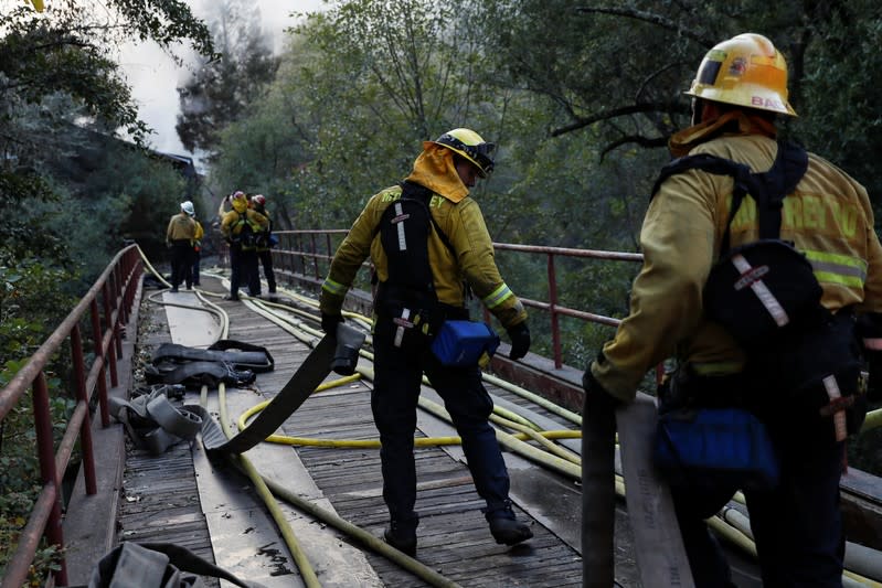 A firefighter works with a hose while working on a burning structure during the Kincade fire in Calistoga, California