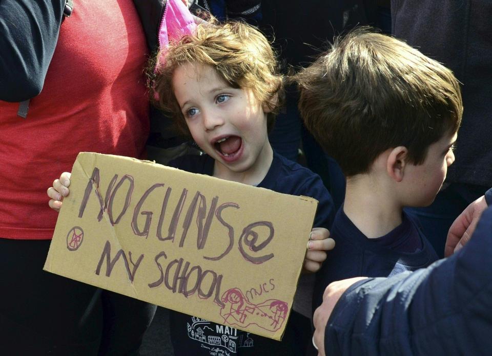 A boy displays his hand-made sign as he poses for a photograph.&nbsp;