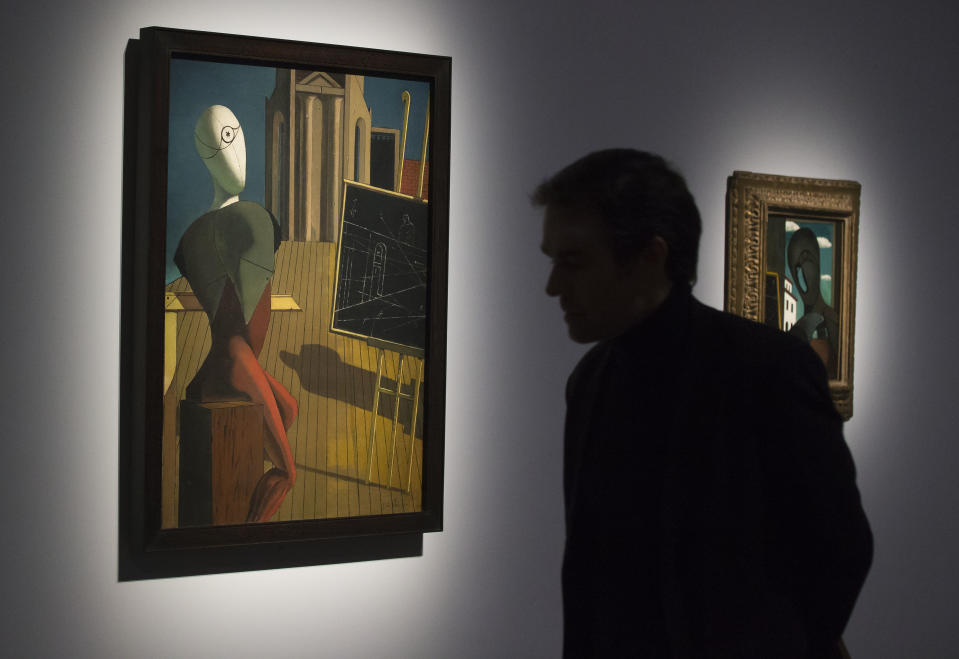 In this photo taken Tuesday, Oct. 29, 2013, a man looks at a painting entitled 'Le Prophete, 1914-1915' by Greek-born Italian artist Giorgio de Chirico, during a press day for the exhibition 'Surrealism and the object', at Pompidou Center in Paris. The exhibition at Paris' Pompidou Center tells the previously untold story of how the Surrealists managed to reconcile their fantastical dreamings and Marxist politics by channeling their artistic message through everyday objects. The exhibition runs from 30 Oct. 30, 2013 until March 3, 2014. (AP Photo/Michel Euler)