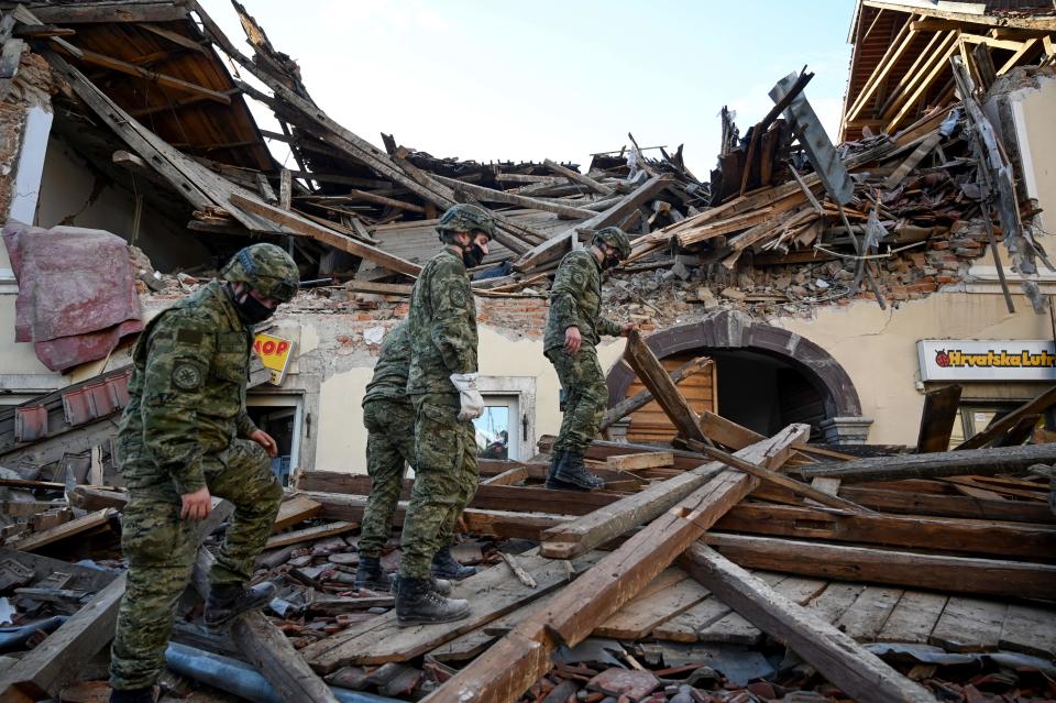 Croatian soldiers walk on wreckage next to damaged buildings in Petrinja, some 50kms from Zagreb, after the town was hit by an earthquake of the magnitude of 6,4 on December 29, 2020. - The tremor, one of the strongest to rock Croatia in recent years, collapsed rooftops in Petrinja, home to some 20,000 people, and left the streets strewn with bricks and other debris. Rescue workers and the army were deployed to search for trapped residents, as a girl was reported dead. (Photo by DENIS LOVROVIC / AFP) (Photo by DENIS LOVROVIC/AFP via Getty Images)