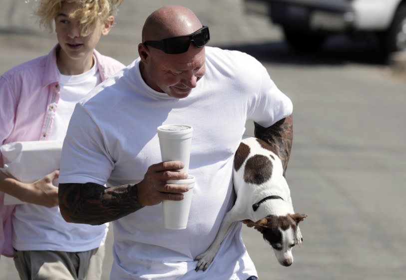 VENTURA, CA - OCTOBER 07: Randy Dinius has his hands full with his dog Ace as he and his son Cash, left, bring lunch for his wife in downtown Ventura on Wednesday, Oct. 7, 2020. Data released by the California Department of Public Health on Tuesday confirmed that Ventura County has moved into the less restrictive red tier. (Myung J. Chun / Los Angeles Times)