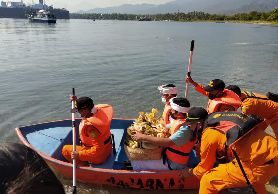 National Search and Rescue Agency personnel help relatives of Capt. Gede Kartika, one of the junior officers of Indonesian Navy submarine KRI Nanggala that sank on April 21, to carry offerings to the sea during a prayer in Celukan Bawang, Bali, Indonesia, Monday, April 26, 2021. Indonesia's military on Sunday officially said all 53 crew members from the submarine that sank and broke apart last week are dead, and that search teams had located the vessel's wreckage on the ocean floor. (AP Photo/Al Rizki)