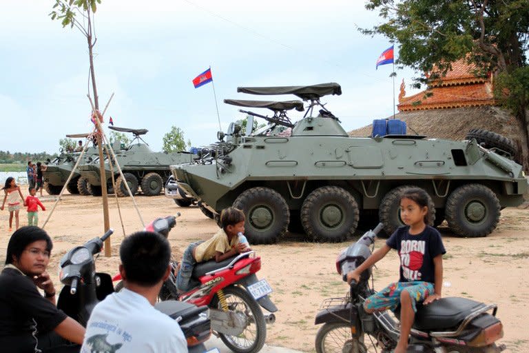 Cambodian children sit on motorbikes near armored personnel carriers on the outskirts of Phnom Penh on August 8, 2013. Cambodia has deployed armed forces in the capital Phnom Penh in case of mass demonstrations following the country’s disputed election