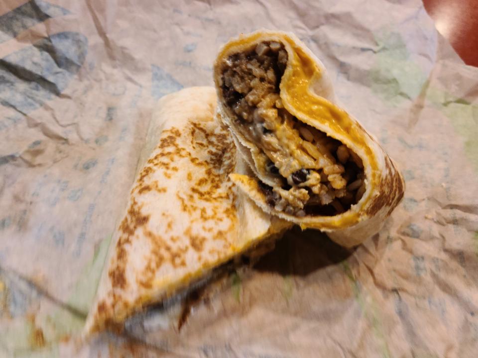 black bean questarito from taco bell cut in half and resting on a paper wrapper