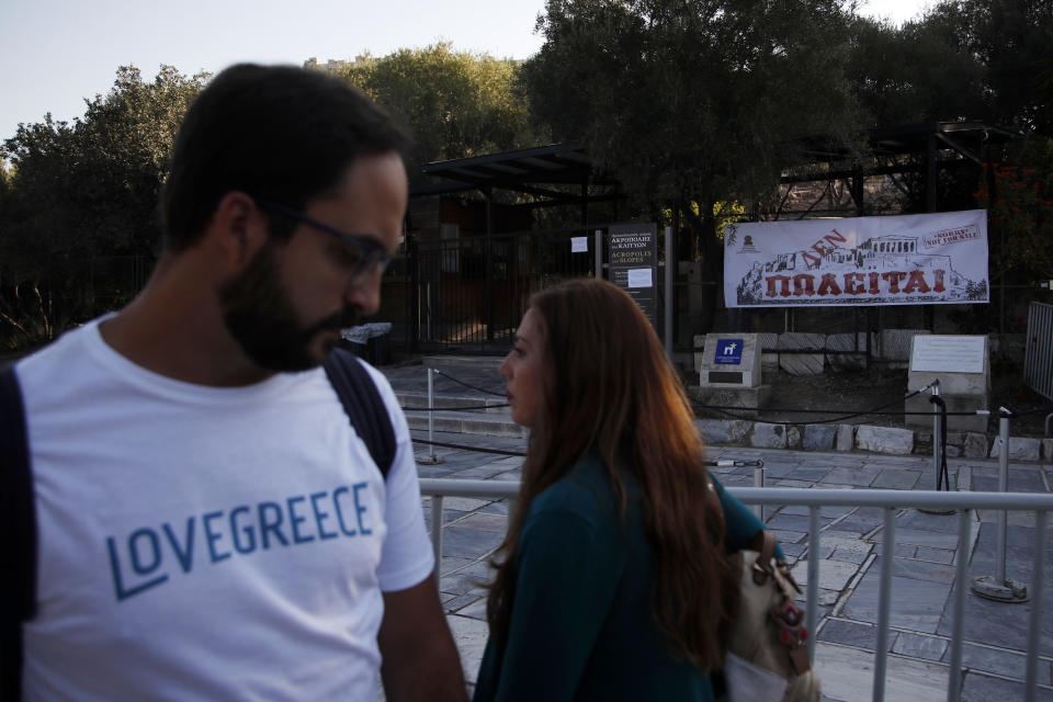 Tourists pass outside the closed Acropolis ancient site in Athens, Thursday, Oct. 11, 2018 during a 24-hour strike called by a Greek union representing staff at the country's ancient site. The union accused the Greek government of failing to list publicly-owned properties that have been transferred to a powerful privatization fund created during the country's international bailouts. The banner depicting Acropolis at the entrance reads in Greek ''Not for Sale.'' (AP Photo/Thanassis Stavrakis)