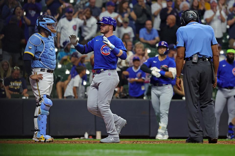Ian Happ of the Cubs crosses home plate in front of Brewers catcher Victor Caratini after smacking a two-run home run in the 10th inning Friday night. Happ had the only two hits for Chicago in the game, both two-run shots.