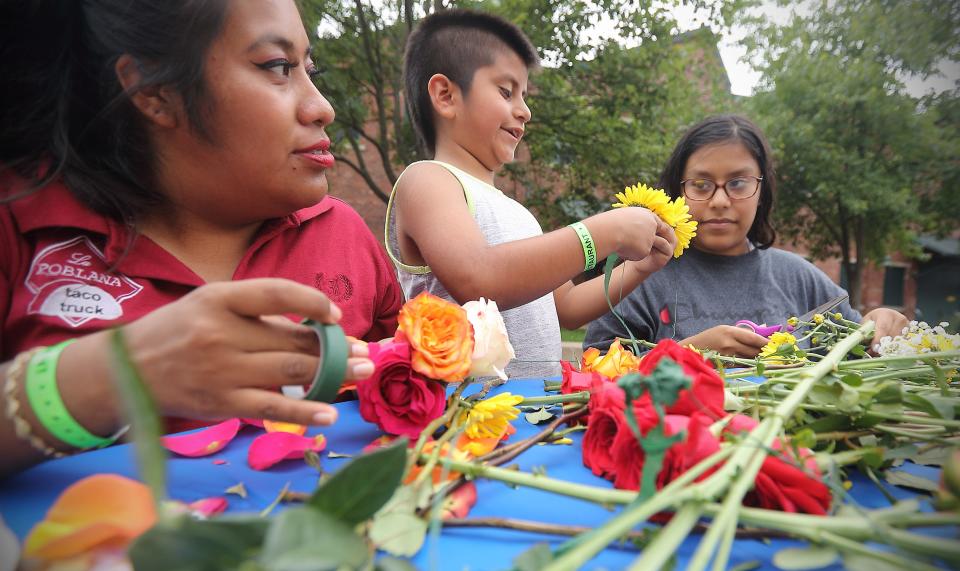 Kimberly Magno, left, Bruce Aguilar, middle, and Jacqueline Aguilar work on making flower crowns in the Playzone at the Taste of Bloomington festival in Showers Plaza Saturday, June 22, 2019. (Rich Janzaruk / Herald-Times)