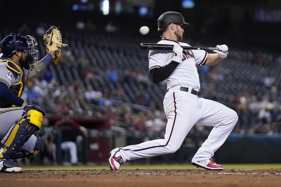 Arizona Diamondbacks' Merrill Kelly backs away from a bunt attempt as Milwaukee Brewers catcher Omar Narvaez, left, reaches out for the inside pitch during the second inning of a baseball game Monday, June 21, 2021, in Phoenix. (AP Photo/Ross D. Franklin)