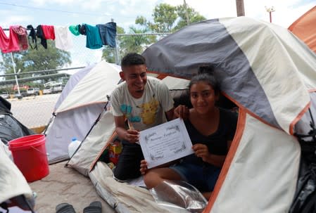 Honduran migrants Marvin Madrid and his new wife Dexy Maldonado show their "Marriage Certificate" during an interview with Reuters in an encampment in Matamoros