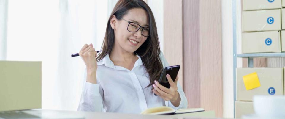 Portrait photo of young Asian business woman feeling happy after receiving product order confirmation from customer by e-mail.