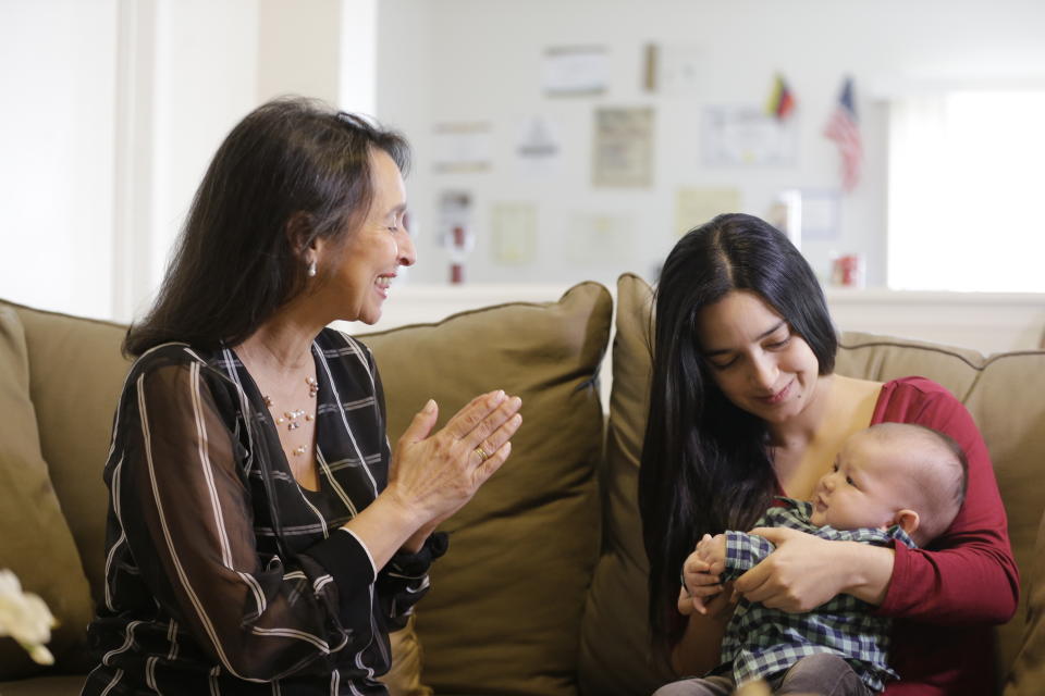 In this March 6, 2020 photo, Cioly Zambrano smiles at her three-month-old grandson held by his mother Maria Fernanda Rangel, in her home in Orlando, Florida. Zambrano, is one of 32 jurists named to the Supreme Court by opposition leader Juan Guaido, immediately converting her and her family into high-priority targets for arrest. Her son Jose Ramon Zambrano who is the baby's father and his wife Marisa Fernanda fled Venezuela the same day Nicolas Maduro’s feared intelligence police raided his family’s B&B. (AP Photo/Cody Jackson)