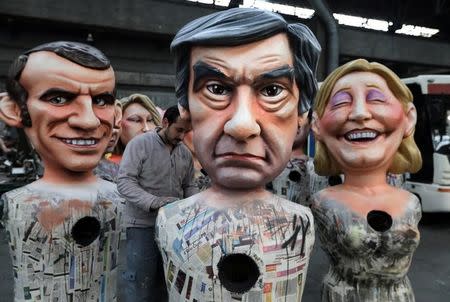 A worker puts the final touches to a giant figure of Francois Fillon (C), former French prime minister, member of The Republicans political party and 2017 presidential candidate of the French centre-right, next to French National Front leader Marine Le Pen (R) and Emmanuel Macron (L), head of the political movement En Marche !, or Onwards !, during preparations for the carnival parade in Nice, France, February 2, 2017. REUTERS/Eric Gaillard/Files