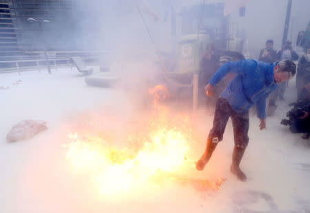 A milk producer tries to extinguish a flare as farmers spray powdered milk to protest against dairy market overcapacity outside a meeting of European Union agriculture ministers in Brussels, Belgium, January 23, 2017. REUTERS/Francois Lenoir