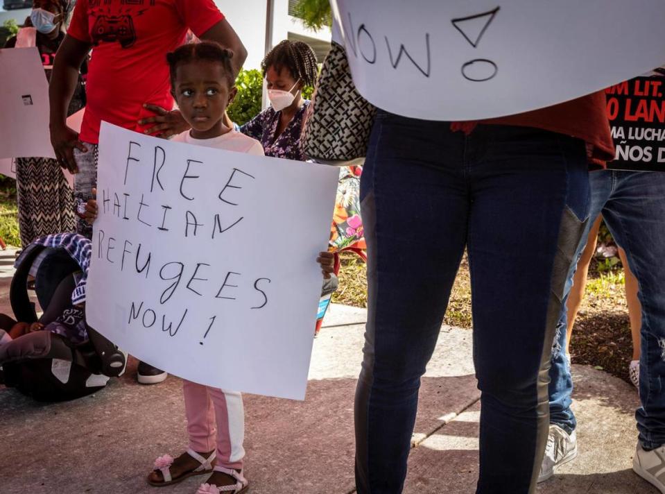 A young girl holds a sign in front of the USCIS district office in Miami on Wednesday, Sept. 22, 2021, during the protest against the Biden administration’s handling of Haitian immigrants at the U.S.-Mexico border.