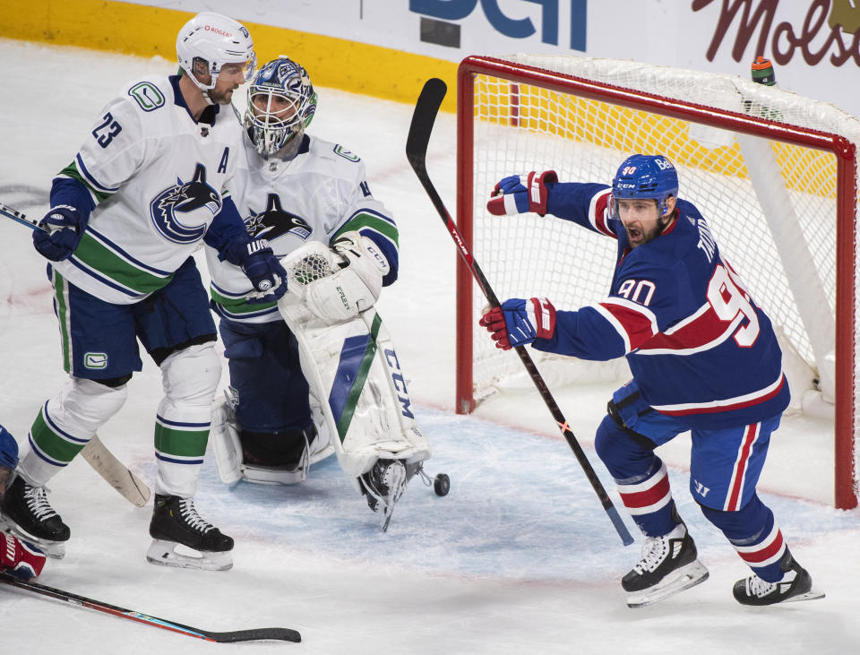 Montreal Canadiens' Tomas Tatar turns to celebrate after scoring on Vancouver Canucks goaltender Braden Holtby as Canucks' Alexander Edler skates nearby during the second period of an NHL hockey game Saturday, March 20, 2021, in Montreal. (Graham Hughes/The Canadian Press via AP)