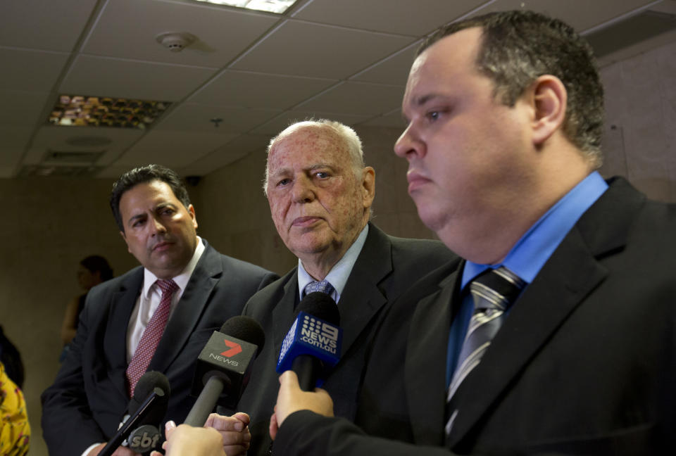 Eduardo Mayr, center, speaks to journalists, as he's flanked by fellow lawyers Mauricio Eduardo Mayr, right, and Anderson Rollenberg, all of whom represent Mario Marcelo Ferreira dos Santos Santoro in Rio de Janeiro, Brazil, Wednesday, Sept. 19, 2018. A pre-trial hearing was held in the case of the Brazilian man, Santoro, charged with killing his former girlfriend in Australia. (AP Photo/Silvia Izquierdo)