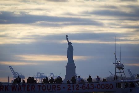 The Statue of Liberty is pictured behind a tourist boat in Battery Park in the Manhattan borough of New York, December 18, 2014. REUTERS/Carlo Allegri