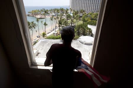 Caretaker Osvaldo "Papo" Marrero looks out from a window of the luxury Normandie Hotel, closed since 2008, in San Juan, Puerto Rico, July 18, 2015. REUTERS/Alvin Baez