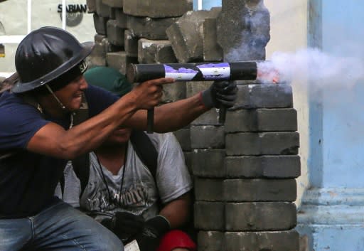 Demonstrators, many of them young men, huddled Saturday behind barricades constructed from cobblestones, felled trees and sheet metal, the ground littered with broken glass and spikes to further guarantee no cars would pass