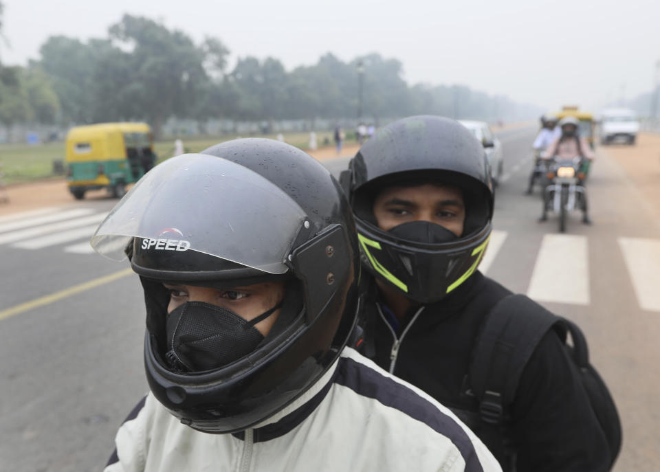 Commuters wear pollution masks and drive on a road on a smoggy afternoon in New Delhi, India, Thursday, Nov. 7, 2019. The air quality index stood at 273 on Thursday after authorities declared a health emergency last weekend when the index crossed 500 — 10 times the level considered healthy by WHO standards. (AP Photo/Manish Swarup)