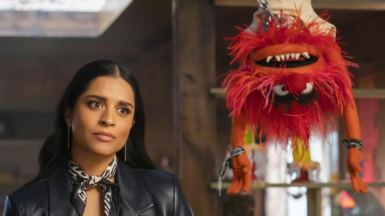  Nora Singh stares at someone off-camera as Animal hangs upside down next to her in The Muppets Mayhem. 