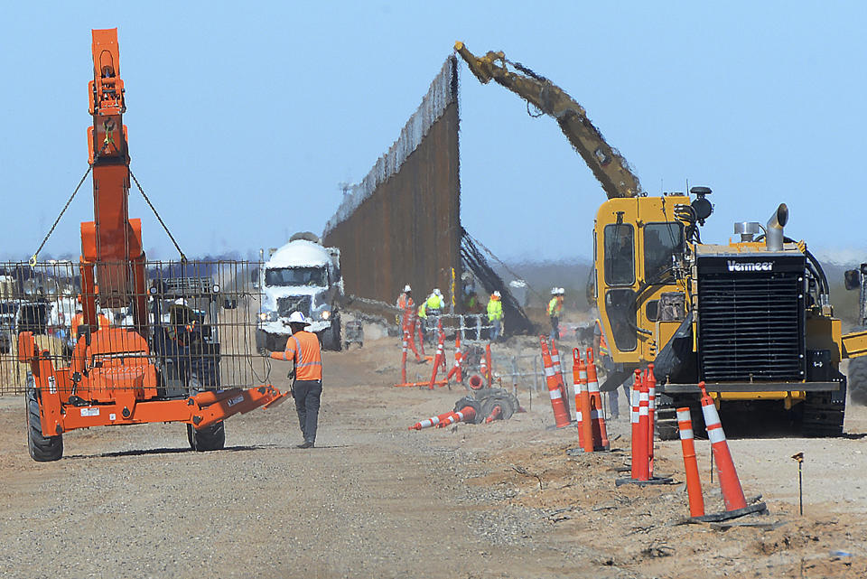 FILE - In this March 23, 2020 file photo, workers install a new section of 30-foot-high "bollard wall" at a construction site south of Yuma, Ariz., near the border between the United States and Mexico. The federal government is proceeding with plans for the border wall even as communities where construction is ongoing protest the presence of workers, according to court documents. On Friday, April 24, 2020 U.S. Rep. Raul Grijalva, D-Arizona, and others held a press call to persuade the government to at least temporarily stop construction. (Randy Hoeft/The Yuma Sun via AP, File)