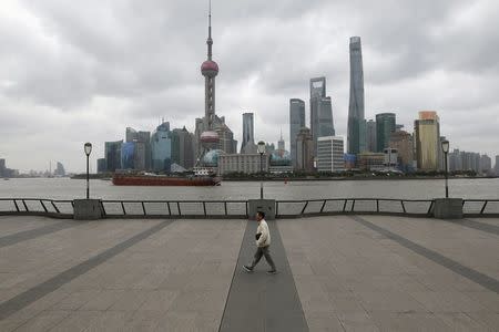 A man walks on the bund in front of the financial district of Pudong in Shanghai, China March 9, 2016. REUTERS/Aly Song