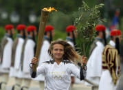 A torchbearer runs with the Olympic flame during a ceremony at Panathenaean stadium in Athens, Thursday, May 17, 2012. The torch begins its 70-day journey to arrive at the opening ceremony of the London 2012 Olympics, from the Greek capital, to cover about 8,000-mile (12,875-kilometer) on its progress over many parts of England to start the games. (AP Photo/Thanassis Stavrakis)