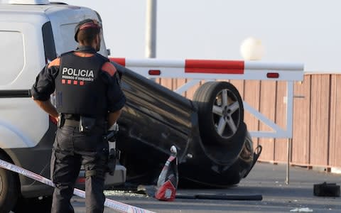 A policeman stands by a car involved in a terrorist attack in Cambrils,  - Credit: LLUIS GENE/AFP