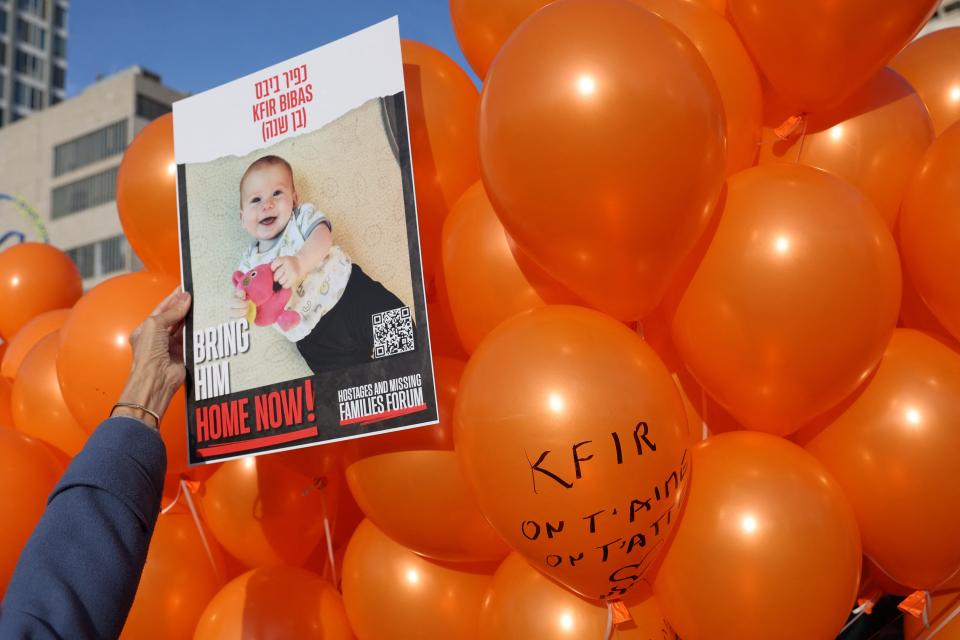 A picture of Kfir Bibas, the youngest hostage to be kidnapped by Hamas militants, is held in front of balloons as Israelis attend his first birthday celebration in Tel Aviv on Thursday.