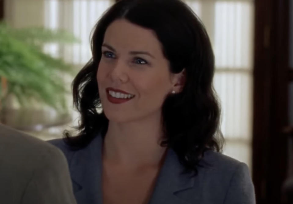 Lauren Graham smiles while wearing a blazer in an indoor setting