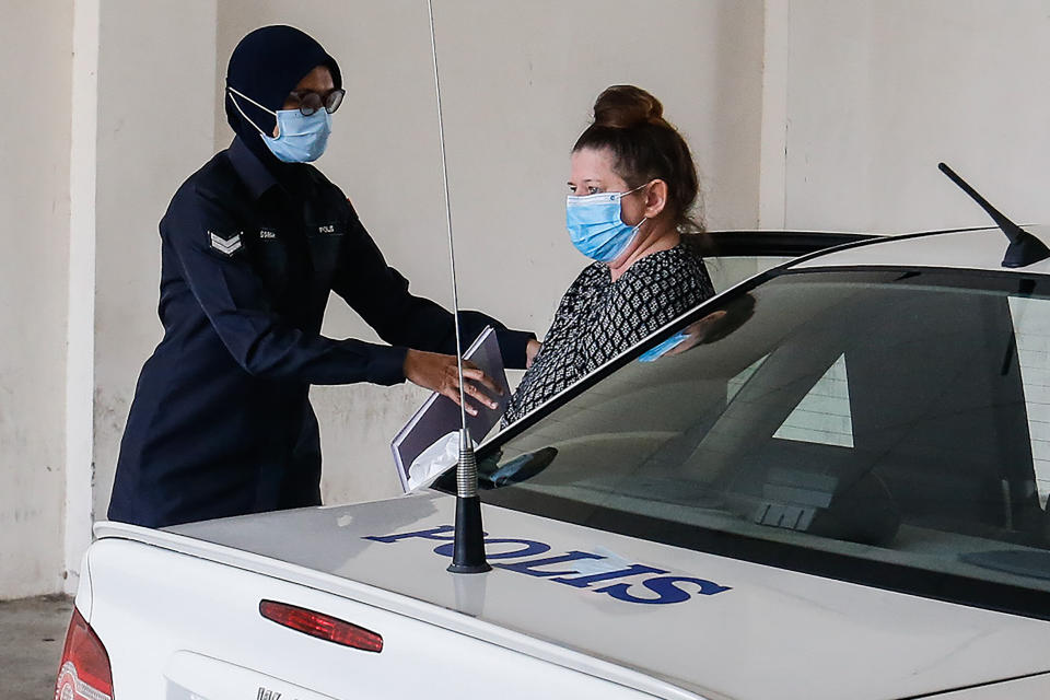 British national Samantha Jones (R), accused of killing her husband in 2018, is escorted by a police officer as she arrives at a court in Alor Setar, in northern Malaysia, on August 3, 2020. - Jones was arrested two years ago after her husband John William Jones was found with a stab wound to his chest in his house on the Malaysian holiday island of Langkawi. (Photo by A. Ammarudin / AFP) (Photo by A. AMMARUDIN/AFP via Getty Images)