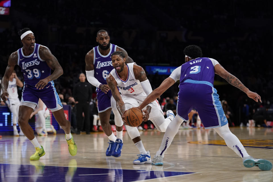 Los Angeles Lakers forward Anthony Davis (3) fouls Los Angeles Clippers guard Paul George (13) during the first half of an NBA basketball game in Los Angeles, Friday, Dec. 3, 2021. Los Angeles Lakers center Dwight Howard (39) and forward LeBron James (6) are at left. (AP Photo/Ashley Landis)