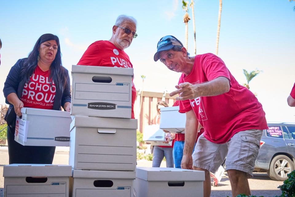 Beth Lewis, Marshall Militano and Mike Garlikov stack the boxes containing signatures for their petition to defer the statewide voucher program to the ballot in the 2024 election on Friday, Sept. 23, 2022, at the Arizona Capitol in Phoenix.