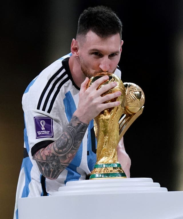 Argentina skipper Lionel Messi kisses the World Cup as he prepares to lift it aloft