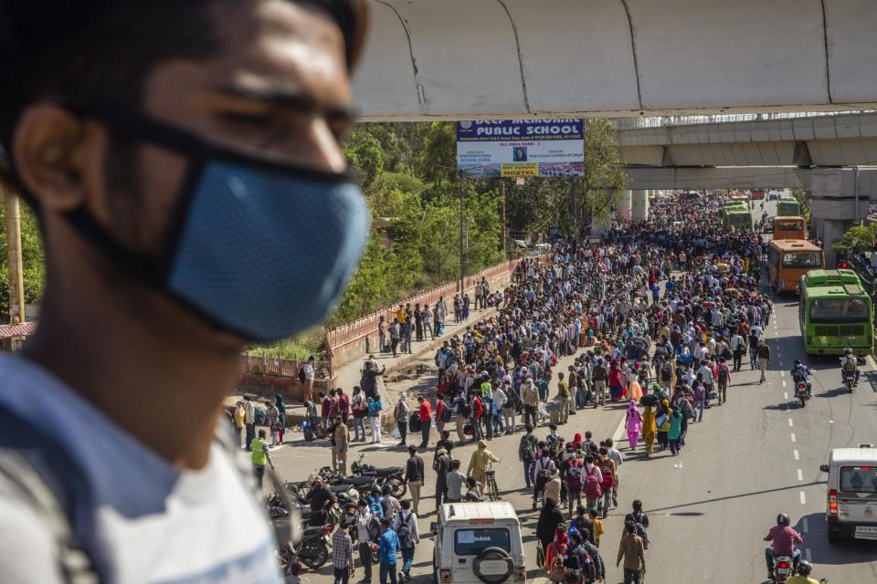 Crowds of Indian migrant workers wait to board buses to return to their native villages amid a nationwide lockdown on March 28 in Ghaziabad, outside New Delhi.